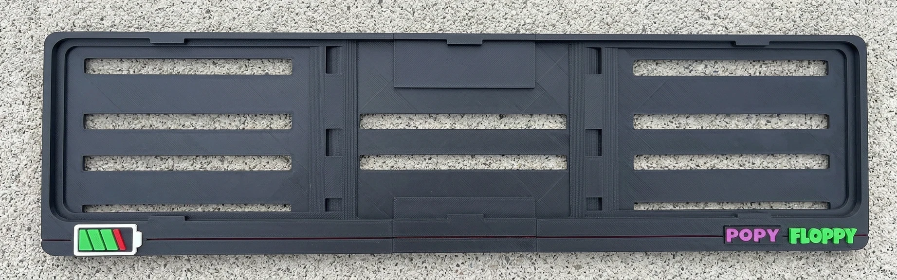 Charged number plate underlay — flat top view showing battery icon and Popy Floppy branding